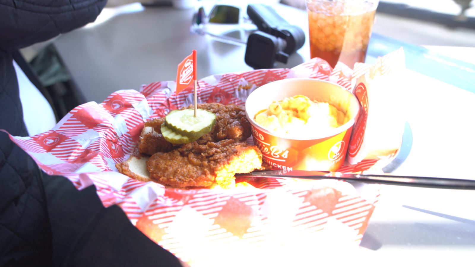 A basket of Nashville hot chicken with a side and a drink at Hattie B’s