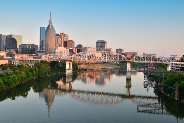 The Nashville skyline and a bridge reflected in the Cumberland River at dusk